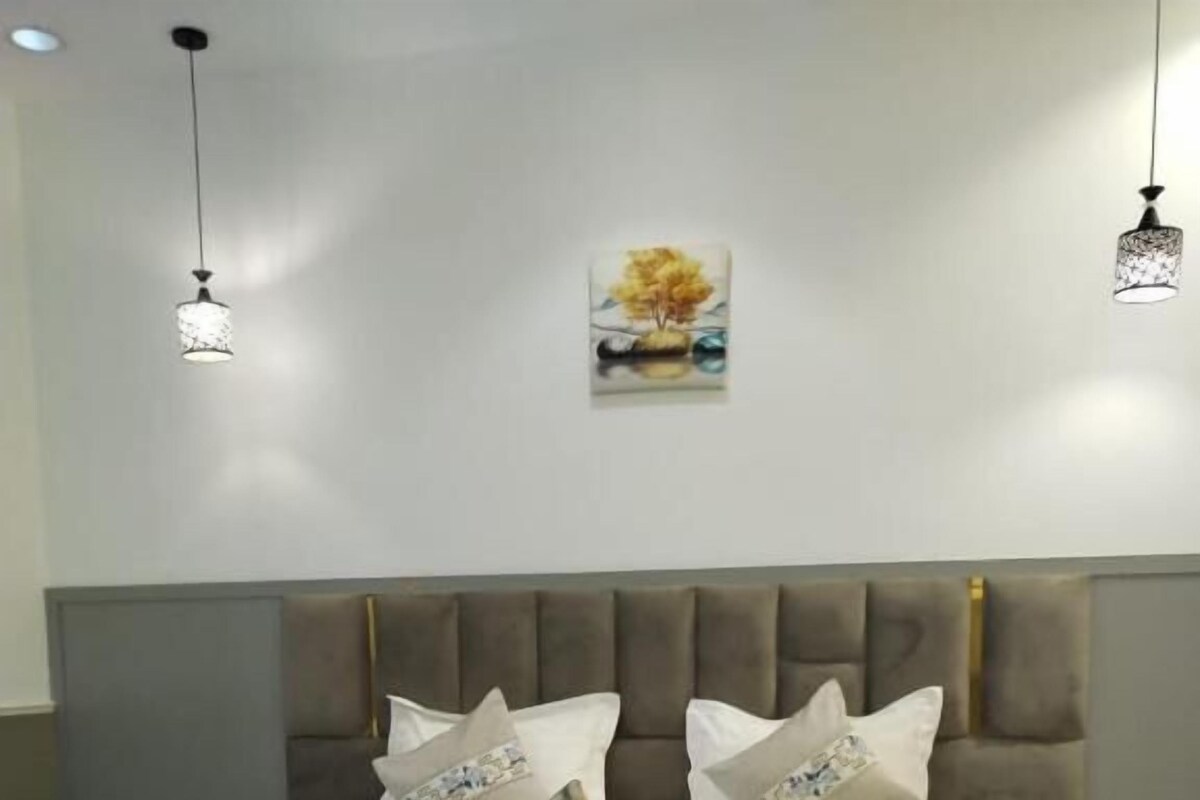 A bedroom with a bed, bedside tables, a sofa, and a wall-mounted artwork.