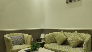Een kamer met een bank, fauteuil en een kleine tafel met een plant.
