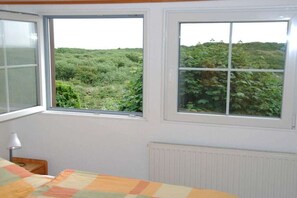 A room with two windows, a bed with a quilt, a lamp, and a radiator.
