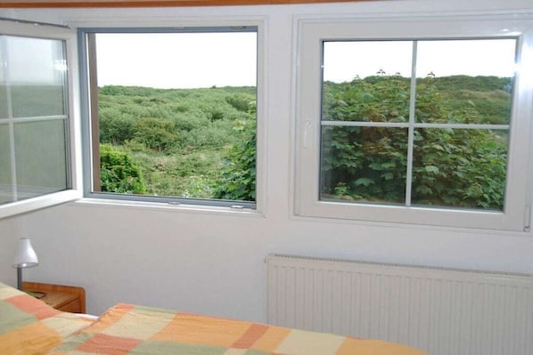 A room with two windows, a bed with a quilt, a lamp, and a radiator.