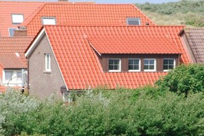 A residential building with a red-tiled roof, multiple windows, and a visible chimney. - Holiday apartment in Juist with swimming pool (Juist)