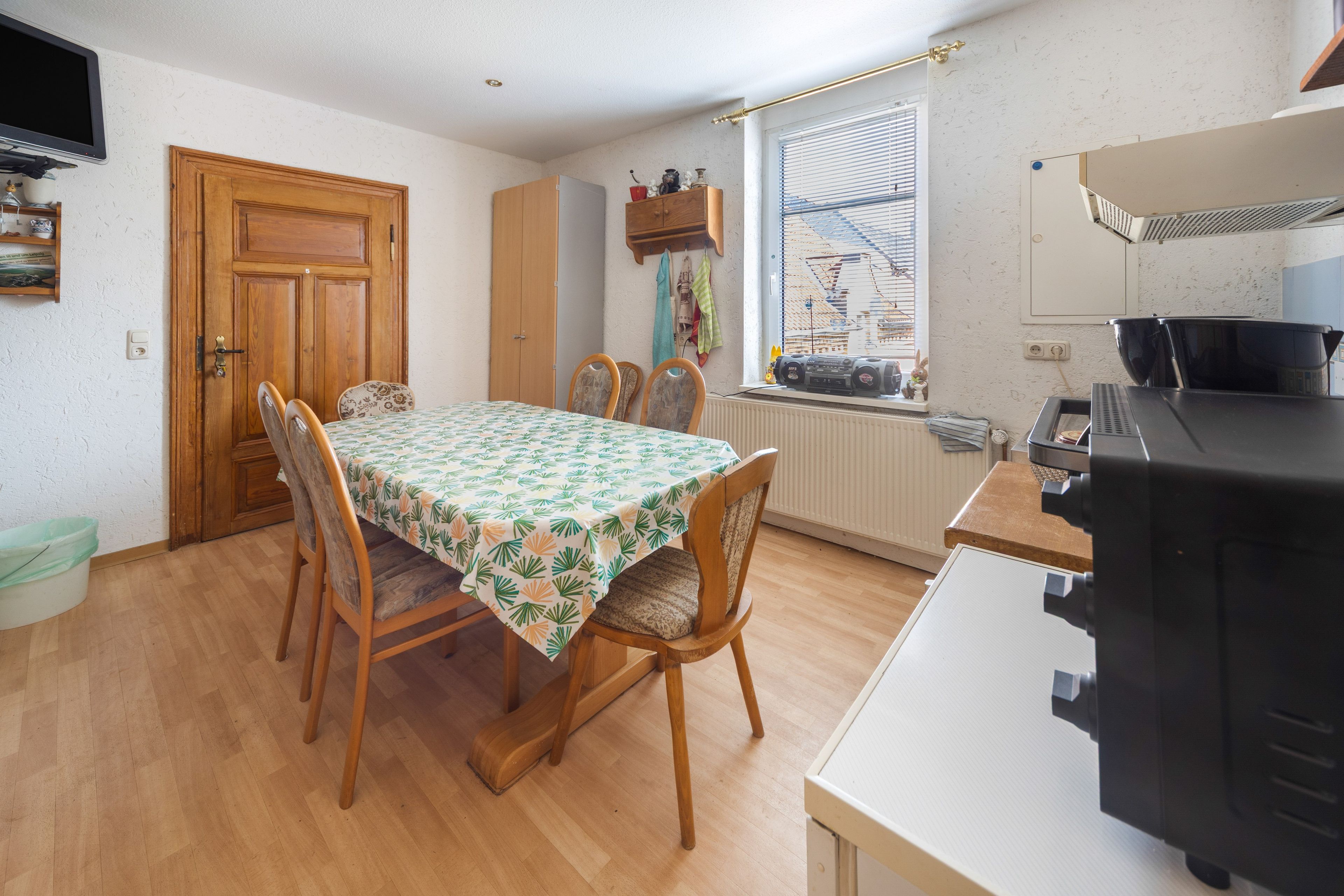 A dining area with a table, chairs, and a window with blinds.