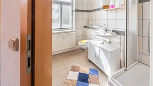 Et badeværelse med toilet, håndvask og brusebad.