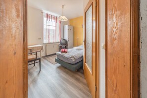 A compact bedroom with a bed, a small desk, a television, and a wardrobe. - Apartment 'Einzelzimmer Am See' with Shared Terrace, Shared Garden and Wi-Fi (Schkeuditz)