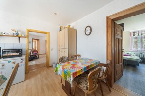 Una cocina compacta con microondas, armarios de madera y un comedor con mantel colorido.