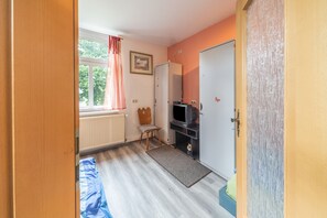 A small room with a bed, a chair, a television, and a door.
