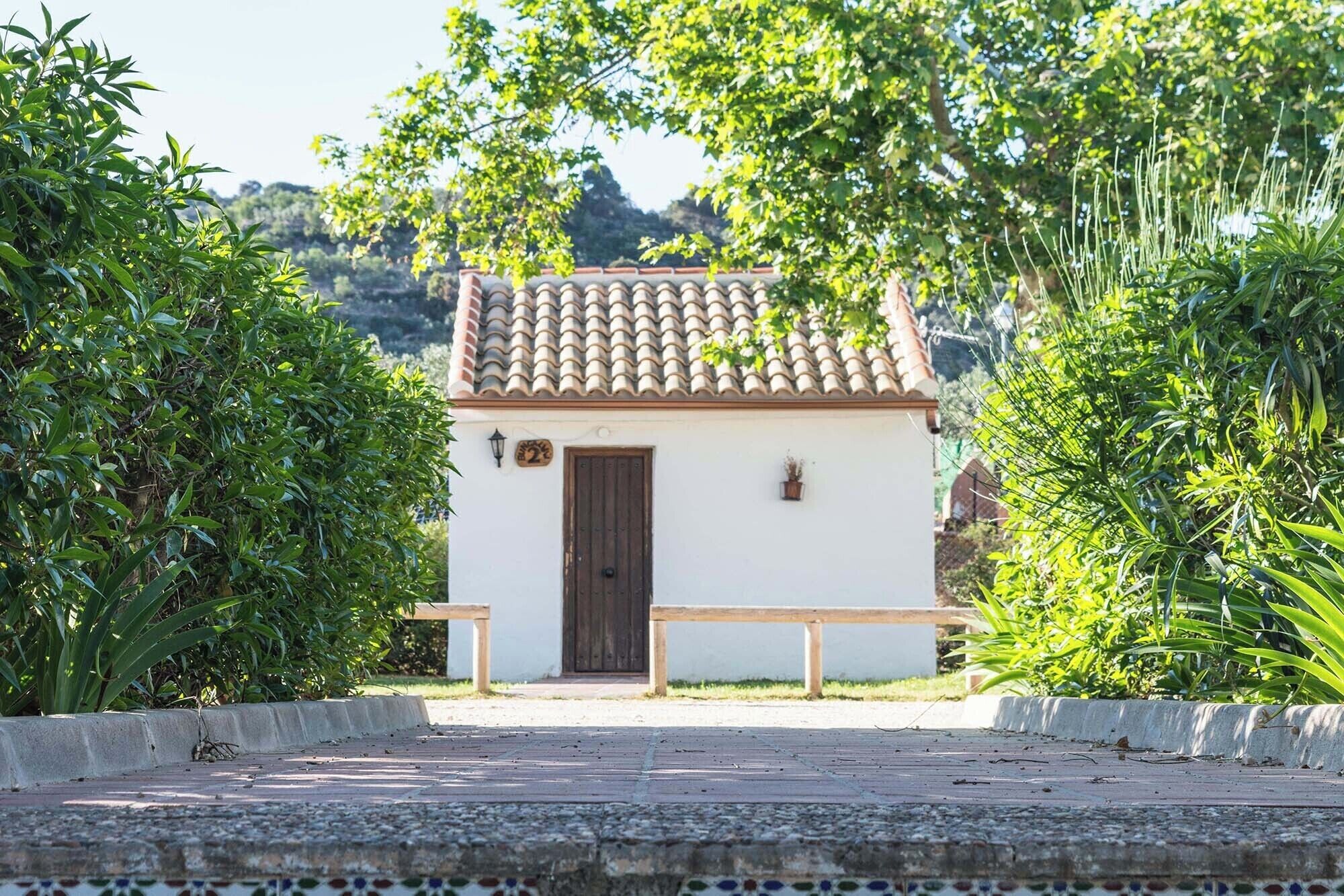 A small building with a tiled roof, a wooden door, and a bench in front.