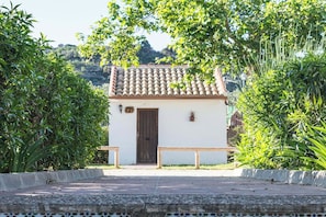 A small building with a tiled roof, a wooden door, and a bench in front.