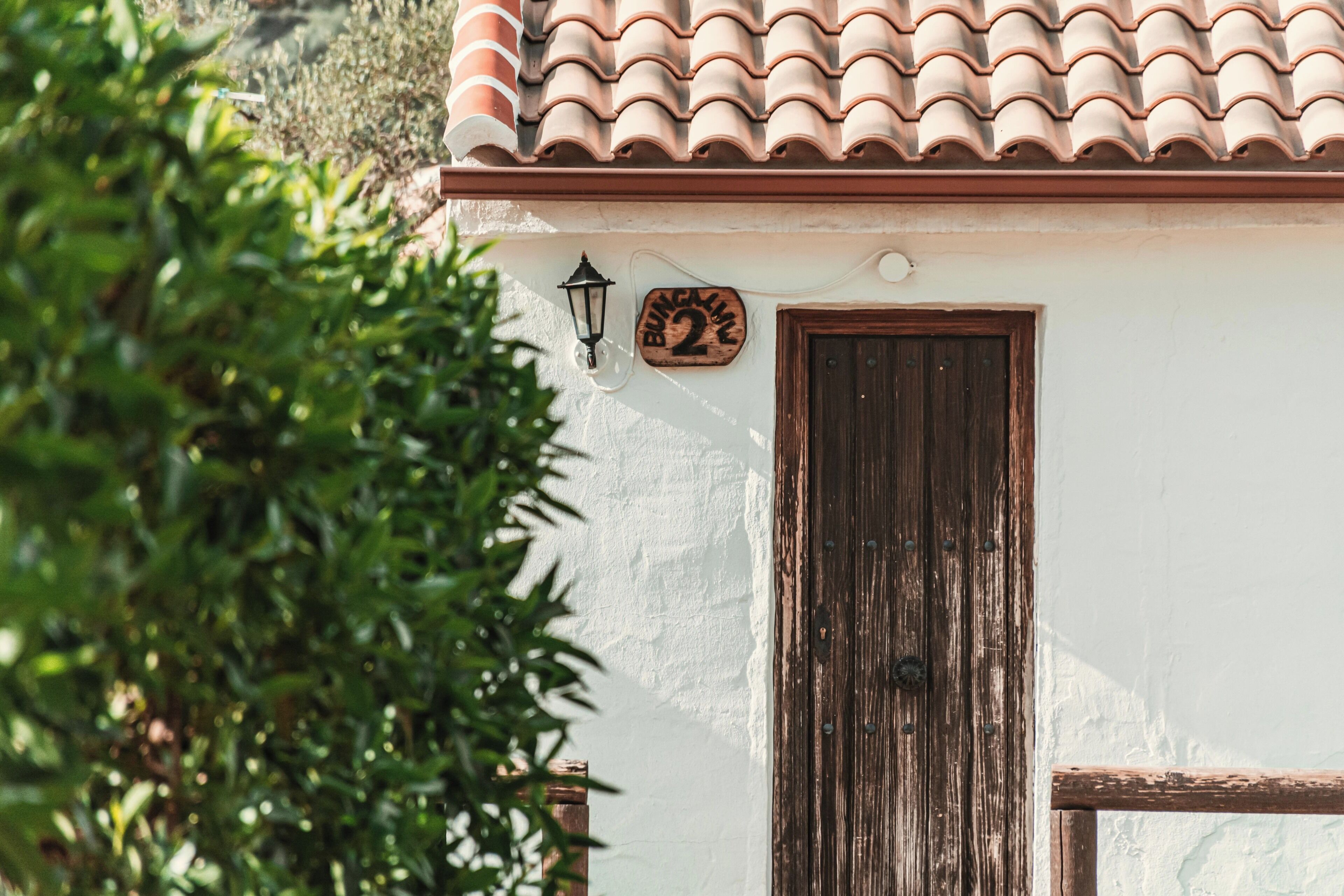 A building with a tiled roof, a wooden door, and a number plaque.