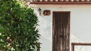 Un bâtiment avec un toit recouvert de tuiles, une porte en bois et une plaque numérotée.