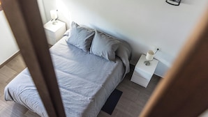 Une chambre à coucher avec un lit, deux tables de chevet et une petite table d’appoint.