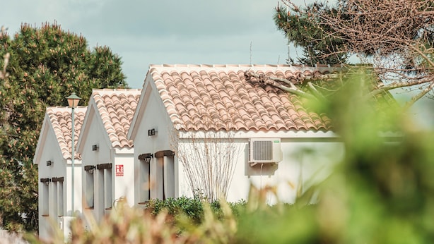 Een rij witte gebouwen met terracottadakpannen, een brandblusser en een airconditioningunit.