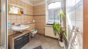 A modern bathroom with a sink, toilet, and window.