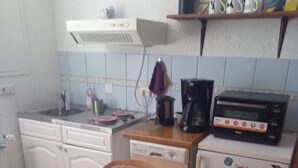 Una cocina compacta con refrigerador, cafetera y microondas.