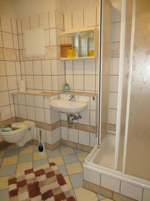 Een badkamer met toilet, wastafel en douche.