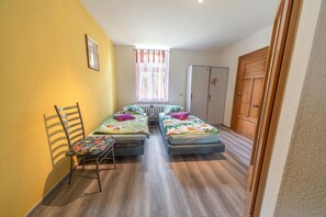 A room with two single beds, a chair, a radiator, a window with curtains, and a wardrobe. - Apartment 'Familienzimmer Am See' with Shared Terrace, Shared Garden and Wi-Fi (Schkeuditz)