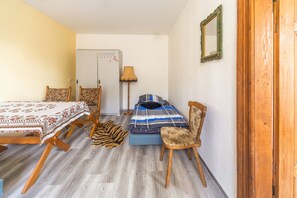 A room with a bed, a chair, a table, and a lamp.
