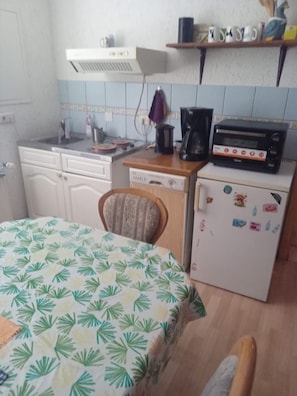 A compact kitchen with a refrigerator, coffee maker, and microwave. - Apartment 'Familienzimmer Am See' with Shared Terrace, Shared Garden and Wi-Fi (Schkeuditz)