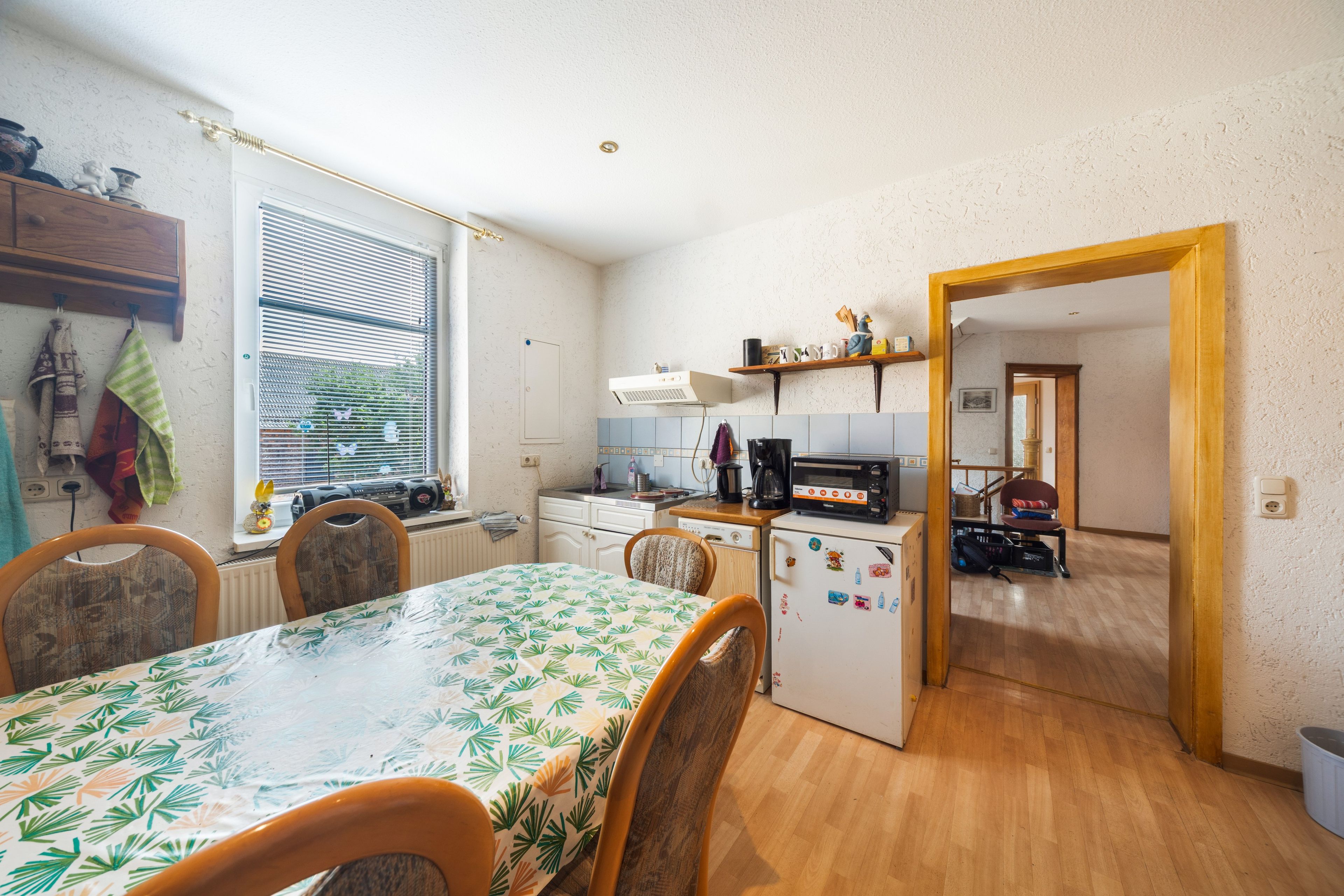 Eine kleine Küche mit Esstisch, Stühlen, Kühlschrank und Mikrowelle.
