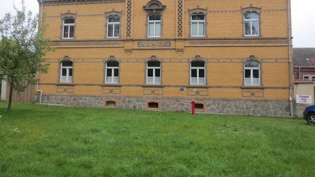 Ein großes, gelbes Backsteingebäude mit vielen Fenstern und einem Steinsockel.