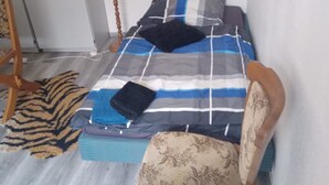 Ein Schlafzimmer mit einem Bett, einem Sessel, einer Lampe und einem Teppich mit Tigerprint.