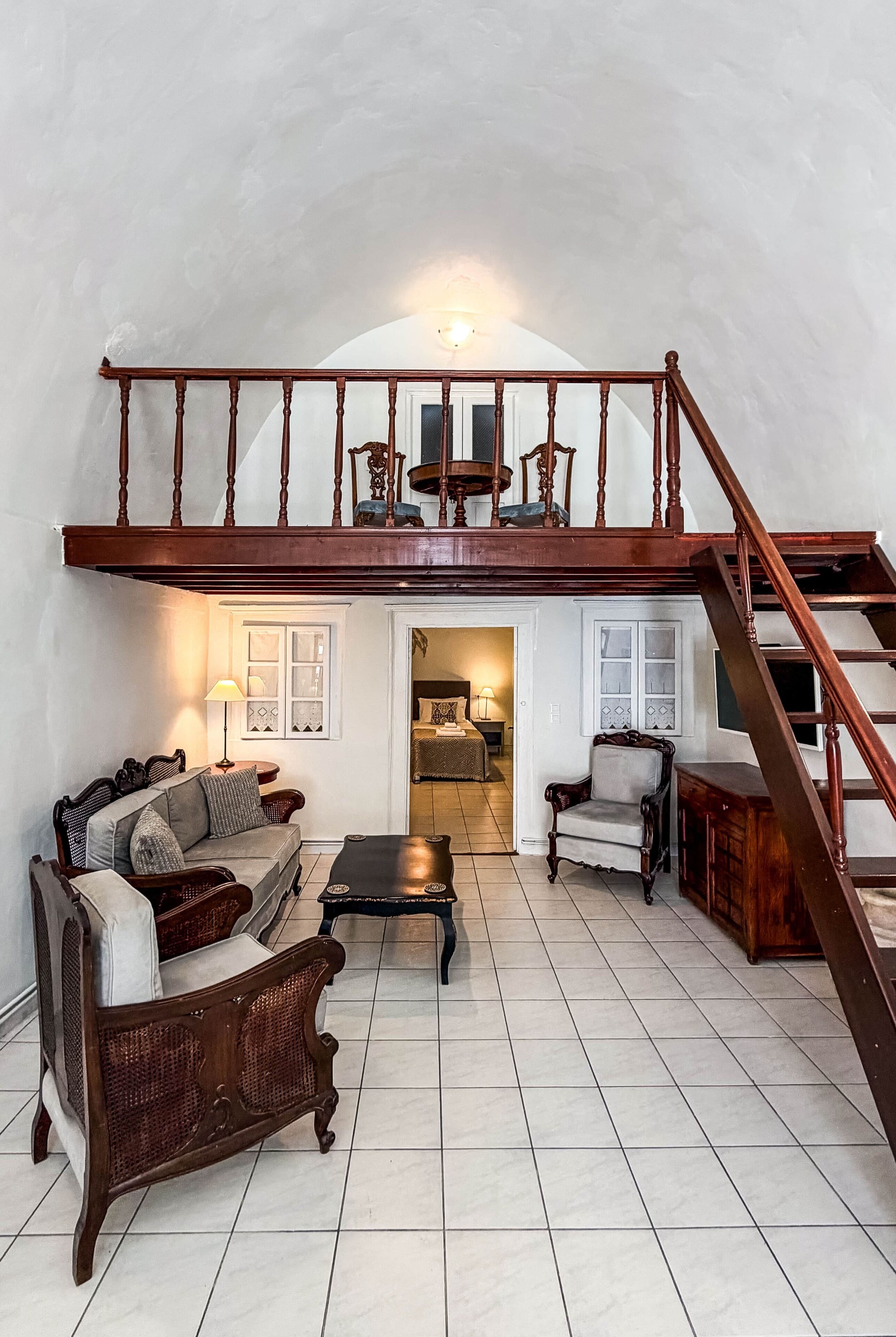 Ein geräumiges Loft mit hoher Decke, einer Holztreppe und einer gemütlichen Sitzecke mit Sofa und Sesseln.
