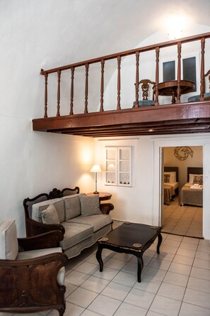 Ein Wohnzimmer mit einer Couch, einem Couchtisch, einer Lampe und einer Treppe, die in eine obere Etage führt.