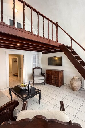 A spacious living area with a staircase, a television, a cabinet, and a dining table. - Villa LuxL Manor House (Mesaria)