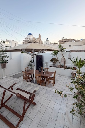 Eine Terrasse mit Holztisch und -stühlen, einem Hängestuhl und Kübelpflanzen.
