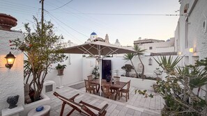An outdoor patio with a table and chairs, surrounded by potted plants and a decorative wall. - Villa LuxL Manor House (Mesaria)