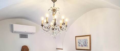 A bedroom with a large bed, a chandelier, a fireplace, and a framed picture on the wall.