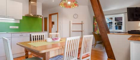 Una cocina moderna con armarios blancos, salpicadero verde y una mesa de comedor de madera con sillas.