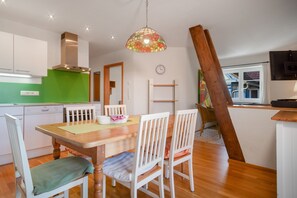 Eine moderne Küche mit weißen Schränken, einer grünen Spritzschutzwand und einem Holzespeise Tisch mit Stühlen.