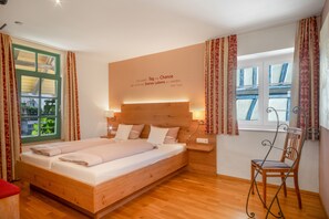 Ein Schlafzimmer mit einem hölzernen Bett, einem Nachttisch, einem Sessel und einem Fenster mit Vorhängen.