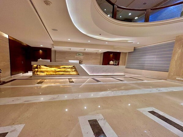 Un vestíbulo moderno con una recepción, un gran muro decorativo y un techo alto con iluminación empotrada.