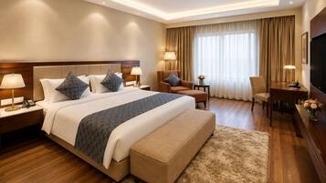 A hotel room with a large bed, a desk, a chair, and a television.
