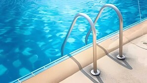 Una piscina amb aigua blava cristal·lina i escales metàl·liques.