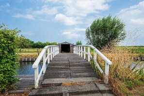 A wooden bridge with white railings leading to a covered structure.