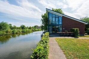 Un bâtiment moderne doté d’une façade en verre, d’une structure extérieure en briques et d’un patio aménagé avec des espaces de détente en plein air.