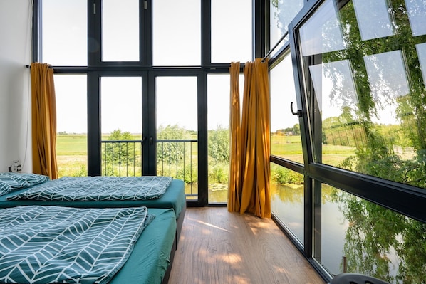 Un dormitorio con una ventana grande, una cama y cortinas.