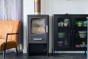 Un salon moderne avec un canapé, un meuble noir aux portes vitrées et une cheminée.
