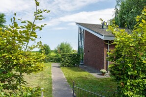A pathway leading to a modern building with large windows and a brick facade.