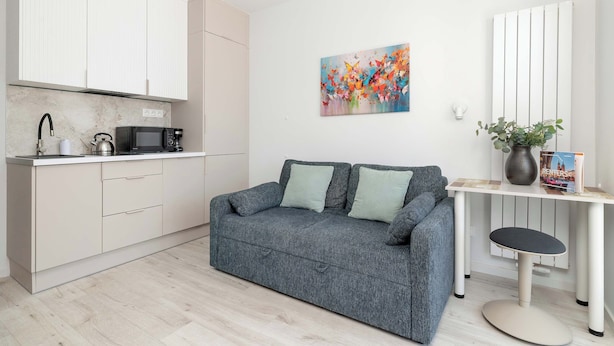 Une cuisine moderne avec des meubles blancs, un four à micro-ondes et une bouilloire.