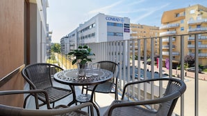 Un balcon avec des fauteuils en osier, une petite table ronde et une plante en pot.