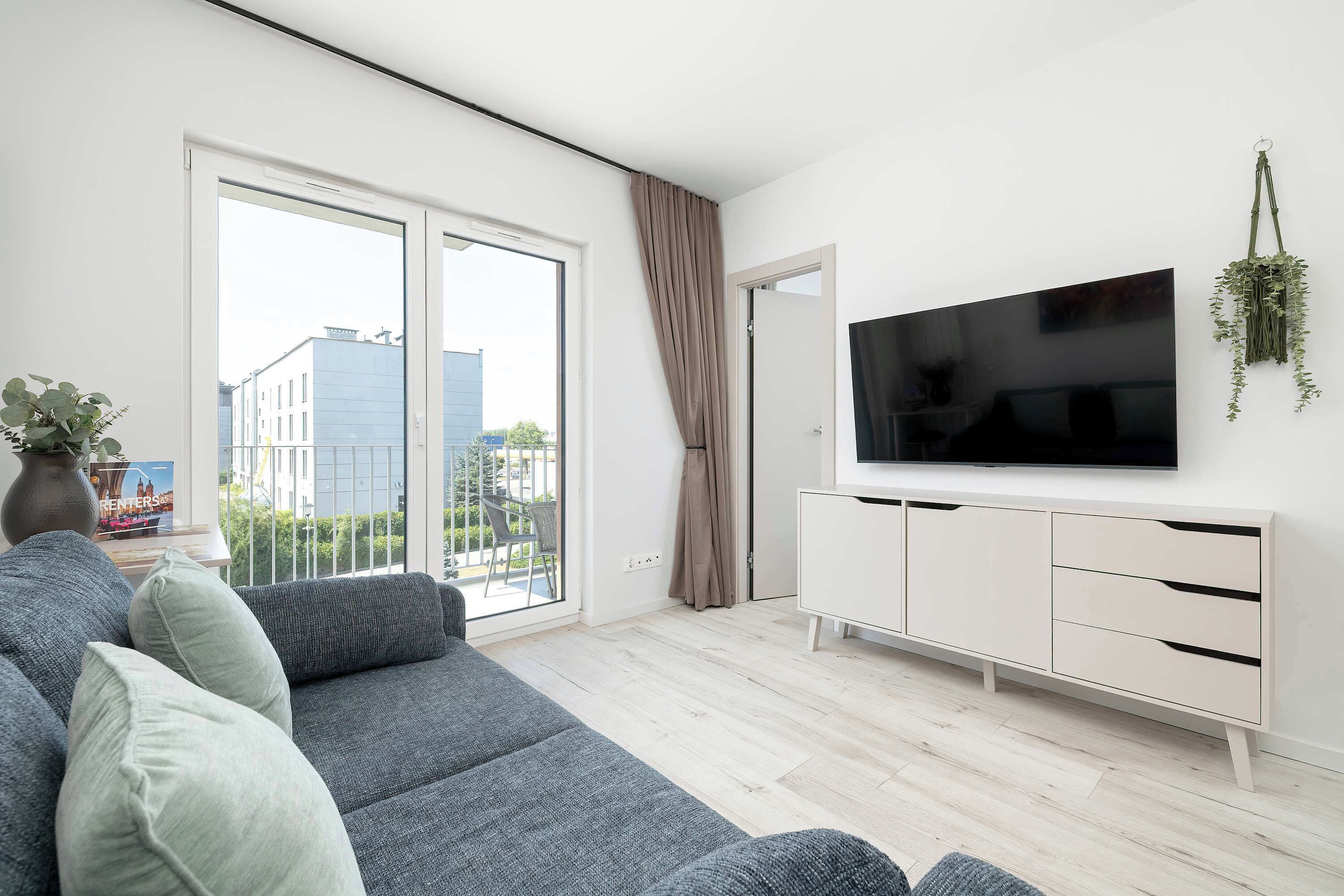 A modern living room with a grey sofa, a flat-screen TV, and a white cabinet.