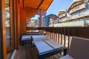 A wooden deck with outdoor seating, overlooking a residential area.