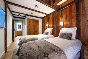 Een hotelkamer met twee bedden, houten lambrisering en een gang naar een andere kamer.