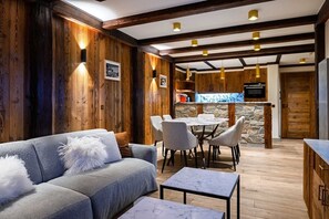 A modern interior with a wooden wall, a dining area, and a kitchen. - Luxury suite 2BR - balcony Courchevel PARK (Courchevel)