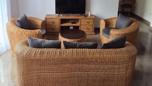 Quarto com televisão de tela plana, móveis de vime e luminária no teto.