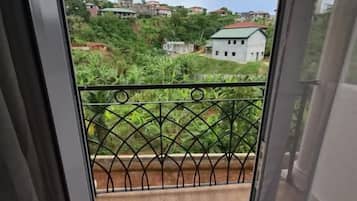 Un balcón con piso de madera y barandilla de metal, con vista a una zona residencial con casas y vegetación.